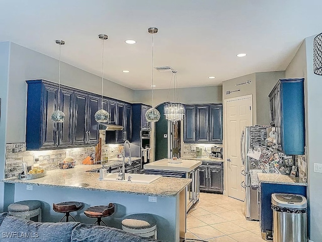 kitchen featuring decorative backsplash, kitchen peninsula, sink, decorative light fixtures, and blue cabinetry