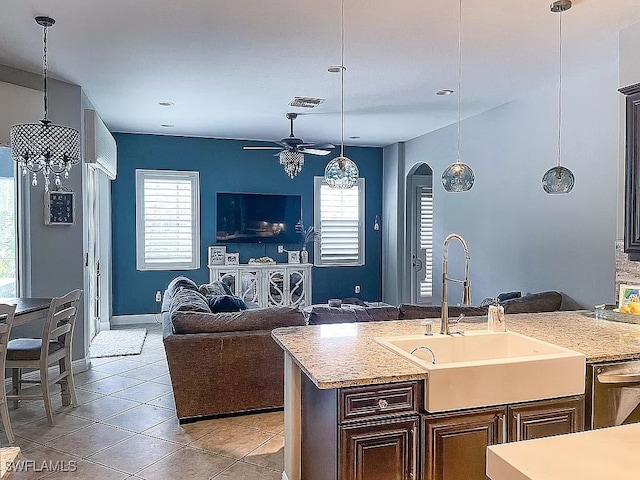 kitchen featuring an island with sink, light stone countertops, sink, and a wealth of natural light