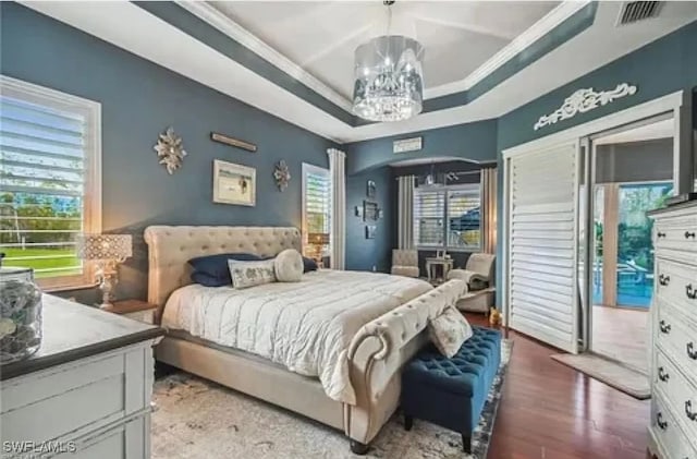 bedroom featuring multiple windows, hardwood / wood-style floors, access to exterior, and a chandelier