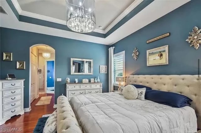 bedroom featuring ornamental molding, dark wood-type flooring, and a tray ceiling