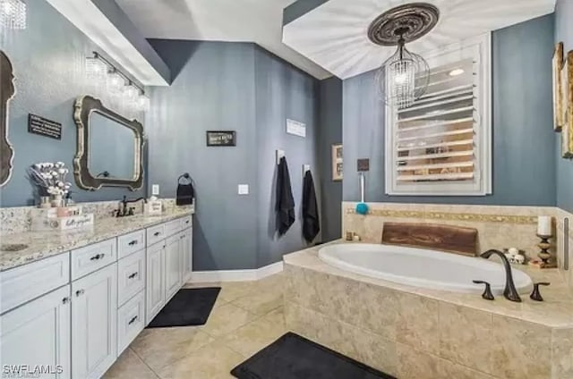 bathroom with vanity, a notable chandelier, tiled tub, and tile patterned flooring