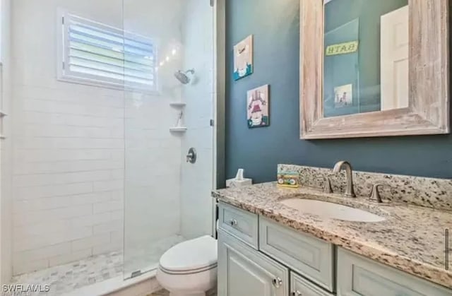 bathroom featuring vanity, toilet, and a tile shower