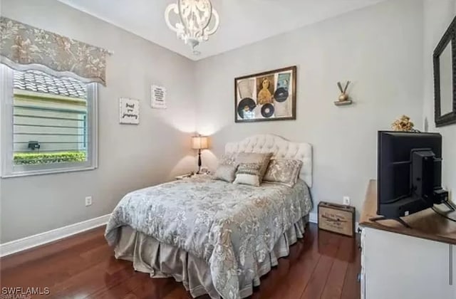 bedroom featuring an inviting chandelier and dark hardwood / wood-style flooring