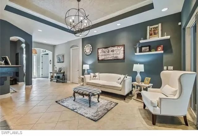 tiled living room with a tray ceiling and an inviting chandelier