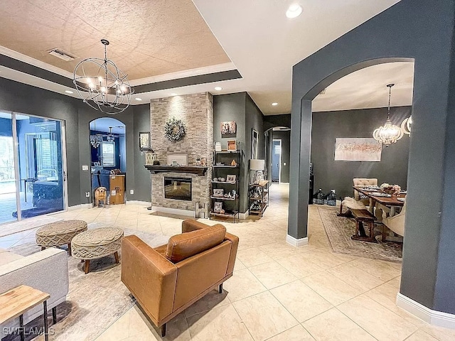 tiled living room featuring a stone fireplace, an inviting chandelier, and a raised ceiling