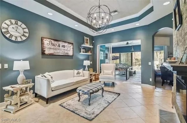 tiled living room featuring crown molding, a tray ceiling, and ceiling fan with notable chandelier