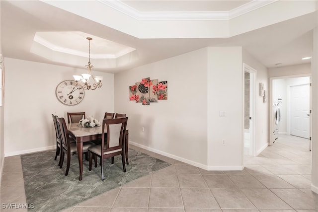 dining area with washer / clothes dryer, a raised ceiling, a notable chandelier, light tile patterned floors, and crown molding