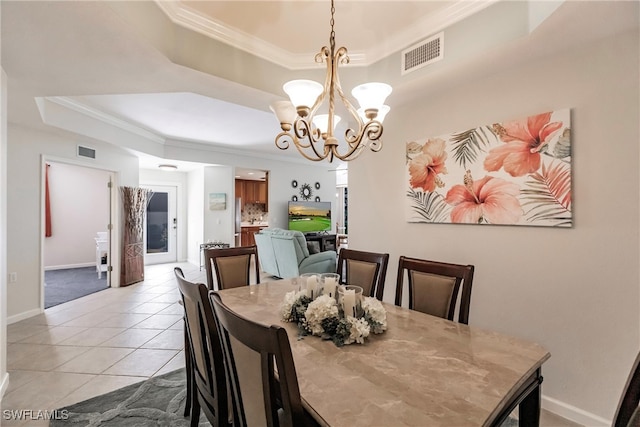 tiled dining room featuring crown molding, an inviting chandelier, and a tray ceiling