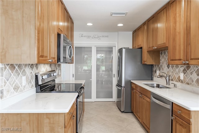 kitchen featuring light stone countertops, backsplash, appliances with stainless steel finishes, and sink