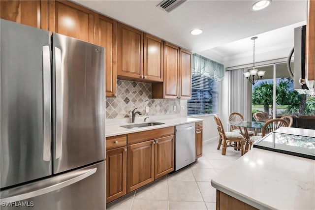 kitchen featuring appliances with stainless steel finishes, decorative backsplash, a notable chandelier, pendant lighting, and sink