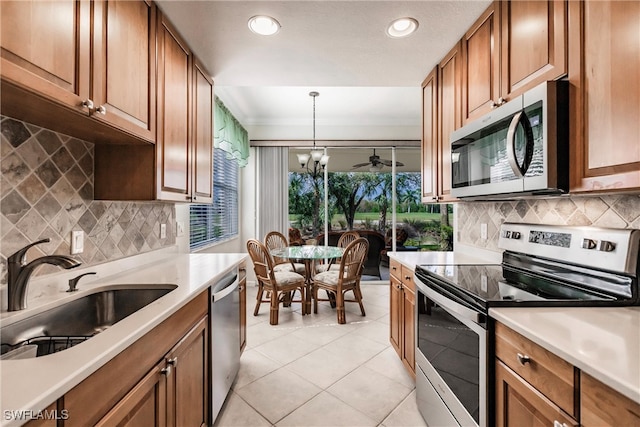 kitchen with decorative light fixtures, sink, an inviting chandelier, light tile patterned flooring, and stainless steel appliances