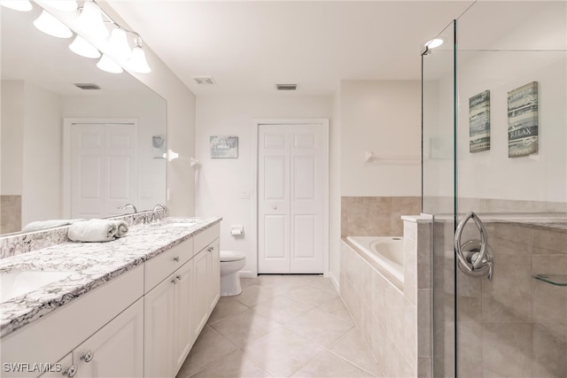 bathroom featuring toilet, vanity, tile patterned flooring, and a relaxing tiled tub