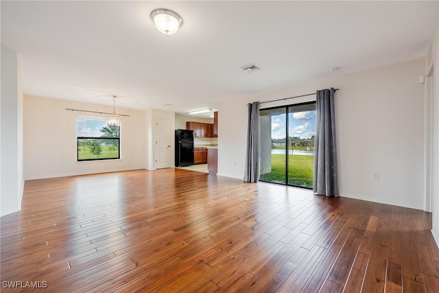 unfurnished living room with a notable chandelier and light hardwood / wood-style floors