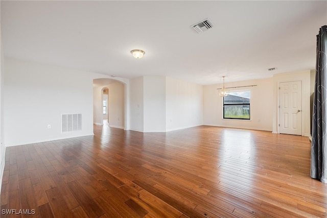 unfurnished room featuring a chandelier and hardwood / wood-style floors