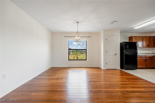 unfurnished dining area with light hardwood / wood-style floors and a chandelier