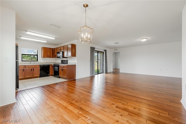 kitchen with black appliances, sink, light hardwood / wood-style floors, decorative light fixtures, and a chandelier