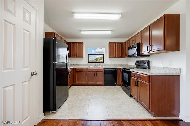 kitchen with light hardwood / wood-style flooring, black appliances, and sink