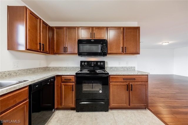 kitchen with black appliances and light hardwood / wood-style flooring