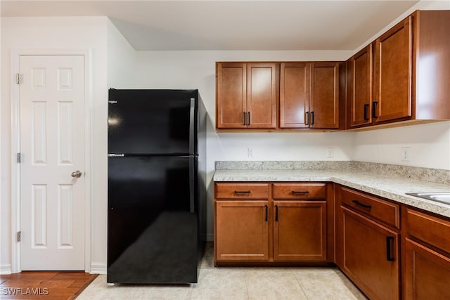 kitchen with black refrigerator and light hardwood / wood-style flooring