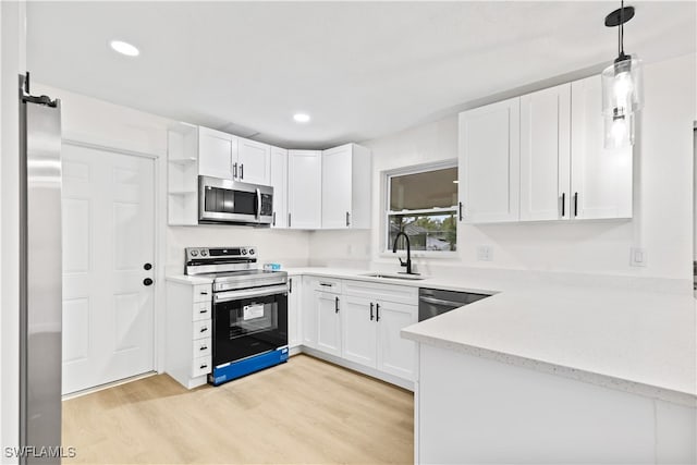 kitchen featuring sink, light hardwood / wood-style floors, stainless steel appliances, decorative light fixtures, and white cabinets