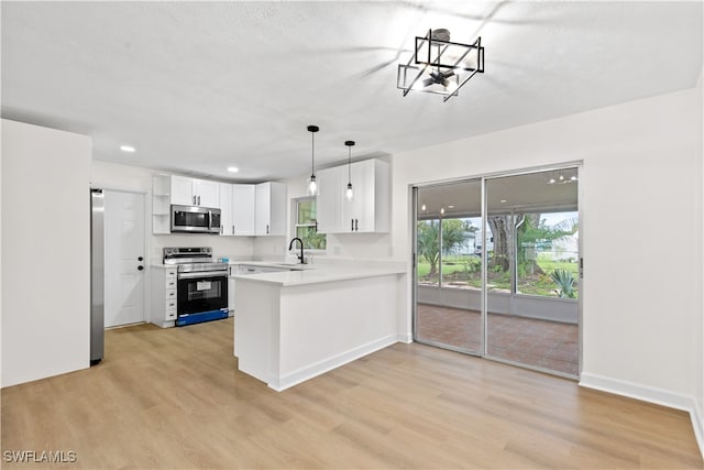 kitchen featuring kitchen peninsula, white cabinetry, light hardwood / wood-style floors, stainless steel appliances, and decorative light fixtures