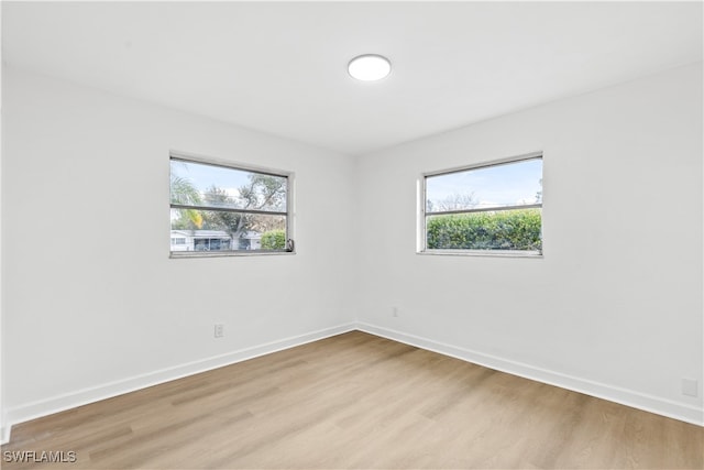 empty room with a wealth of natural light and light hardwood / wood-style floors