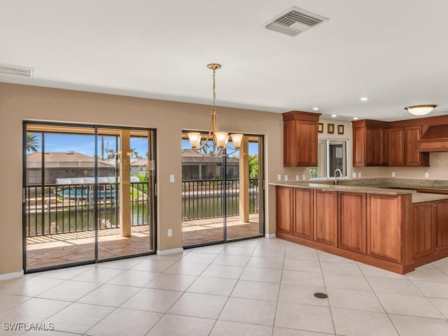 kitchen featuring a water view, a healthy amount of sunlight, decorative light fixtures, and an inviting chandelier