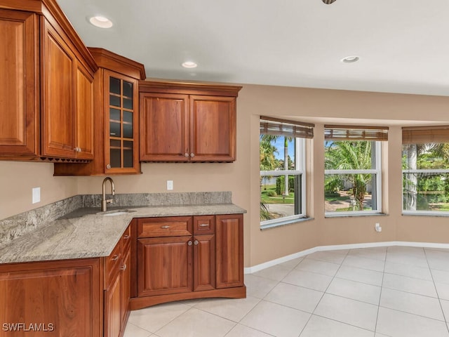 kitchen featuring light stone countertops, light tile patterned floors, and sink