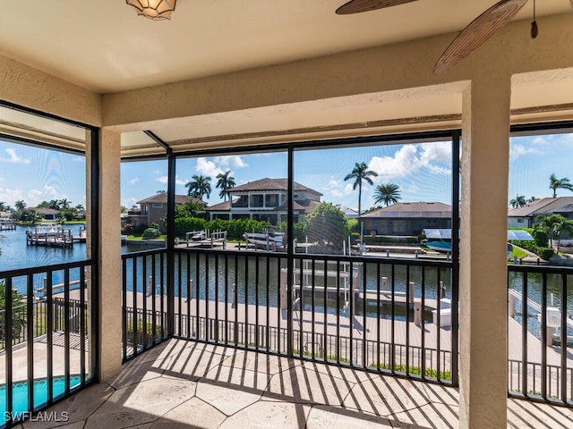 sunroom / solarium with plenty of natural light, ceiling fan, and a water view