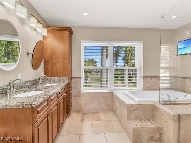 bathroom with tile patterned flooring, vanity, and tiled tub