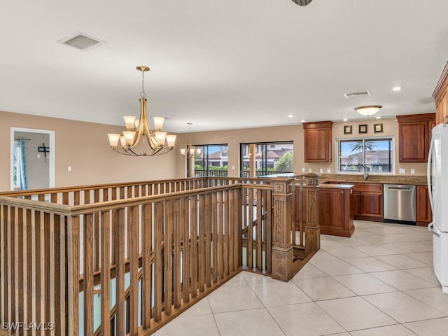 hallway with light tile patterned floors, a notable chandelier, and sink