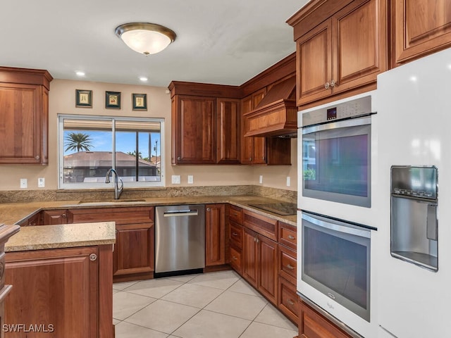 kitchen featuring light stone counters, custom range hood, stainless steel appliances, sink, and light tile patterned floors