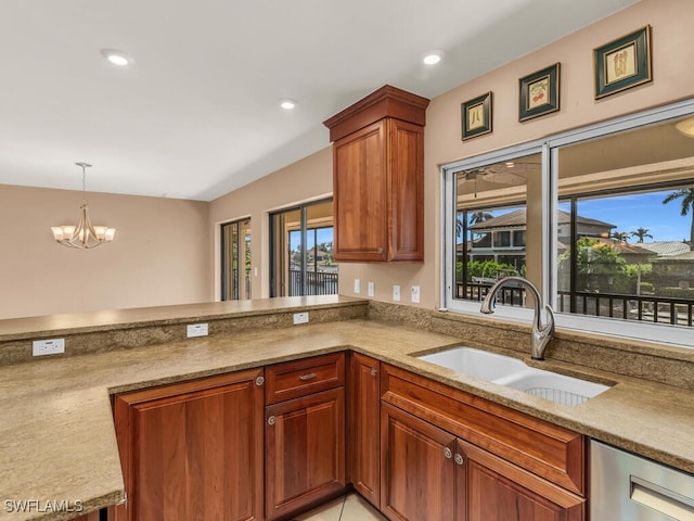 kitchen featuring light stone countertops, sink, a notable chandelier, kitchen peninsula, and decorative light fixtures