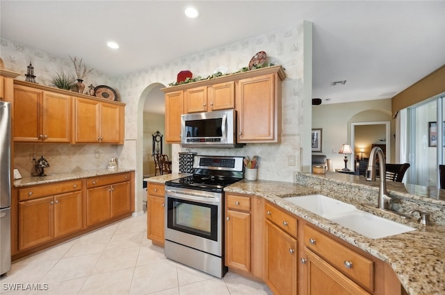 kitchen featuring stainless steel appliances, sink, light stone counters, and light tile patterned floors