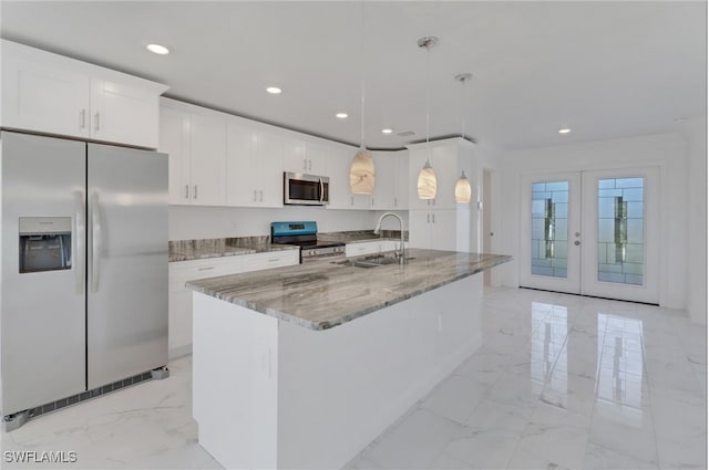 kitchen with stainless steel appliances, hanging light fixtures, an island with sink, white cabinets, and french doors