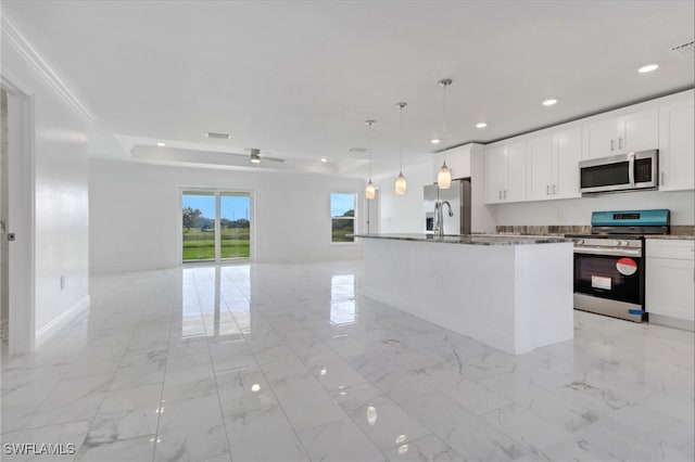 kitchen with an island with sink, hanging light fixtures, white cabinets, and appliances with stainless steel finishes