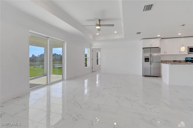 unfurnished living room with ceiling fan and a raised ceiling