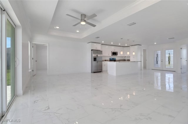 unfurnished living room featuring french doors, plenty of natural light, ceiling fan, and a tray ceiling