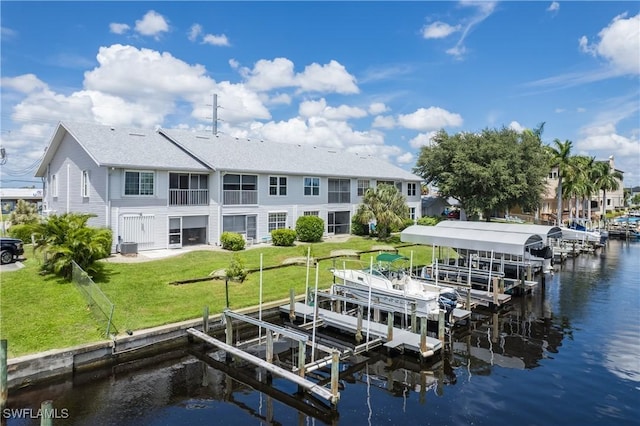 dock area with a water view, boat lift, and a lawn