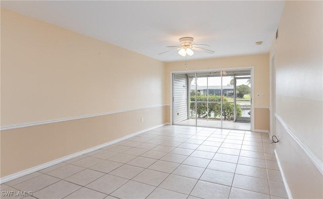 empty room with light tile patterned flooring, ceiling fan, and baseboards