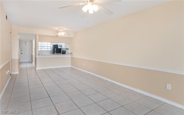 empty room with ceiling fan, baseboards, and light tile patterned flooring