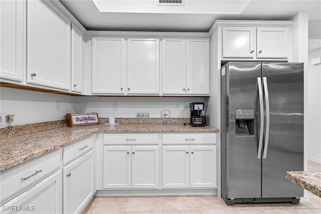 kitchen featuring white cabinetry, light stone counters, light tile patterned floors, and stainless steel fridge with ice dispenser