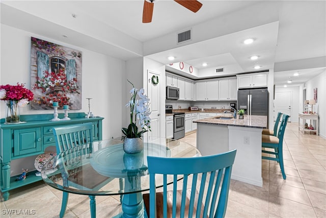 tiled dining space with ceiling fan and sink