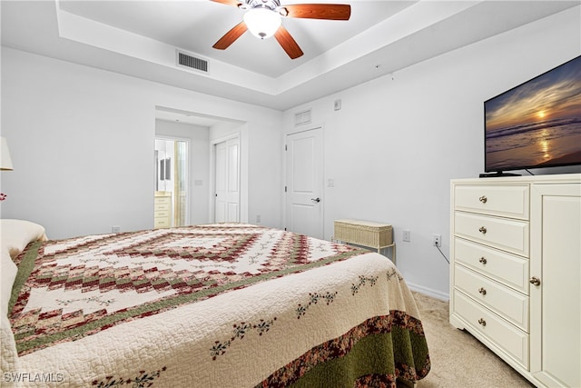 bedroom featuring light colored carpet, a raised ceiling, and ceiling fan