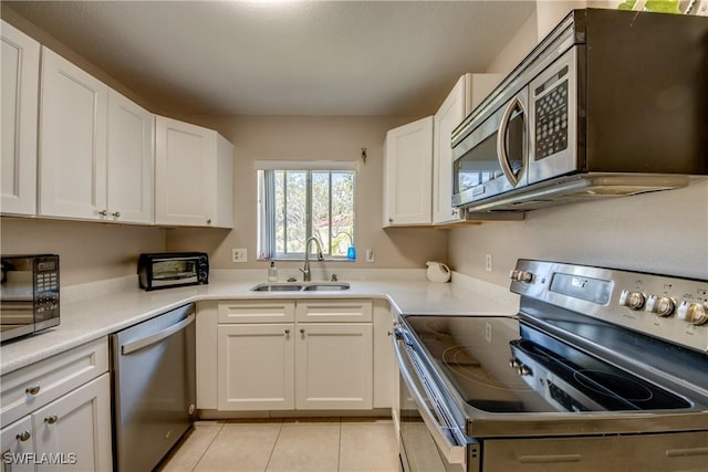 kitchen with stainless steel appliances, white cabinetry, sink, and light tile patterned floors