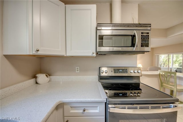 kitchen featuring white cabinetry, light stone countertops, and appliances with stainless steel finishes