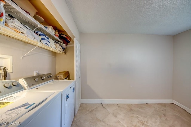 clothes washing area featuring washer and clothes dryer and a textured ceiling