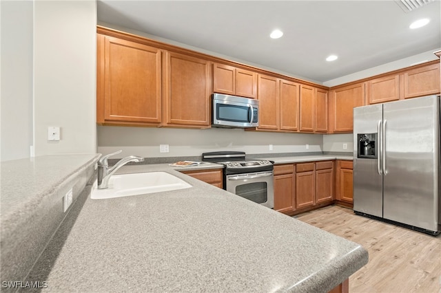 kitchen featuring appliances with stainless steel finishes, light hardwood / wood-style floors, and sink