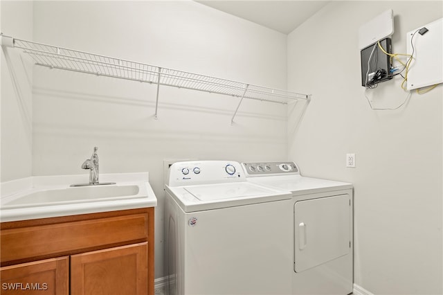 clothes washing area with cabinets, washer and clothes dryer, and sink