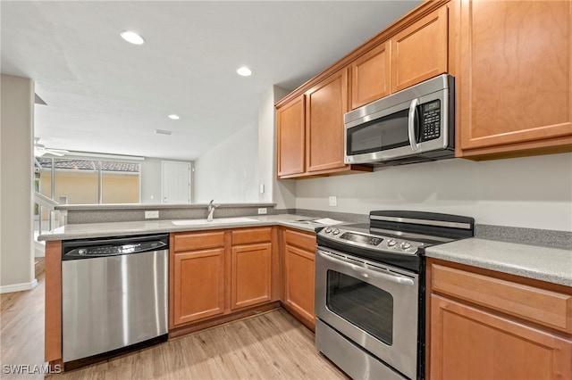 kitchen featuring ceiling fan, light hardwood / wood-style floors, kitchen peninsula, sink, and stainless steel appliances